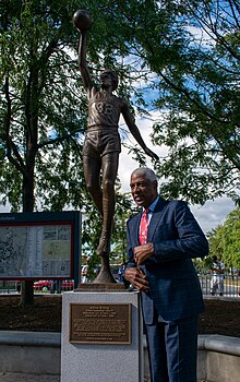 Erving standing next to the statue depicting his likeness at the UMass unveiling ceremony in Amherst, Mass., in September 2021.