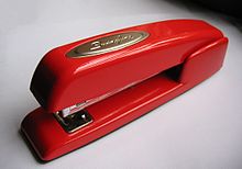 A small red stapler with the badge reading "Swingline" atop, seen from above on a white background with shadow at the top of the image
