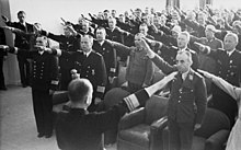 Photograph of dozens of Wehrmacht officers standing in a room and performing the Nazi salute