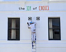 A QR code being painted on the side of a building