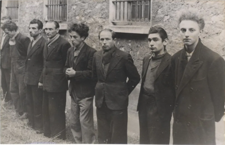 Photographie en noir et blanc d'un groupe de huit hommes réuni à l'extérieur d'un bâtiment.