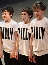 Three young boys are performing cheerfully
