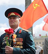 Member of the Armed Forces of Belarus pays tribute to the Victory Day in 2014, in front of a Soviet flag