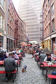 Looking east from the eastern section of Stone Street, with dining tables on either side of the cobblestone street