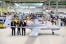 Traja muži stoja za dronom, malým bezpilotným lietadlom