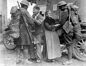زوجان فرنسيان مسنَّان في إحدى المدن الفرنسية المُحتلة من قبل القوات الألمانية لمدة أربع سنوات يرحبان بجنديين أمريكيين، 6 نوفمبر 1918