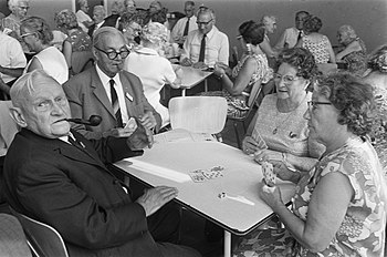 photo of older adults sitting around a table, playing cards