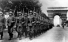 Soldiers walking down Champs-Élysées, with Arc de Triomphe in the back