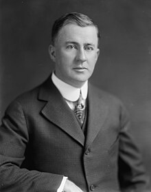 Black-and-white photo of a cleanshaven man, about 45, wearing a suit and tie.
