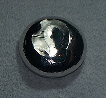 A flattened drop of dark gray substance