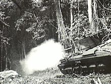 A tank fires into the jungle.