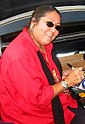 A woman wearing sunglasses and a red jacket signing a compact disc