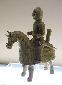 Photo of a glazed terracotta statue showing a horse and its rider, both decked in lamellar armour