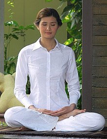 Молода жінка медитує в позі напівлотоса