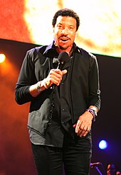 A man standing on stage, singing into a microphone