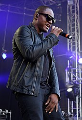 A picture of a man wearing sunglasses and singing with a microphone