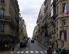 Photographie en couleurs, représentant une rue parisienne et des immeubles.