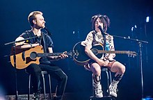 Billie Eilish and Finneas O'Connell, holding their acoustic guitars