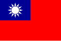 Một lá cờ màu đỏ, với một hình chữ nhật nhỏ màu xanh ở góc trên cùng bên trái, trên đó có một mặt trời màu trắng bao gồm một vòng tròn được bao quanh bởi 12 tia.