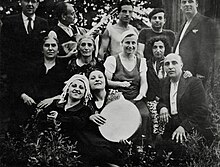 Photographie en noir et blanc d'un groupe d'hommes et de femmes, dont certains jouent d'instruments de musique.