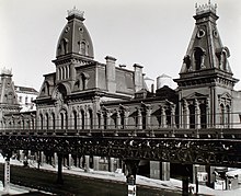 The Third Avenue Car Barn, a Second Empire car barn with mansard roofs, central and end towers, as seen from beyond the Third Avenue elevated railroad line. The car barn was demolished to make way for Manhattan House.