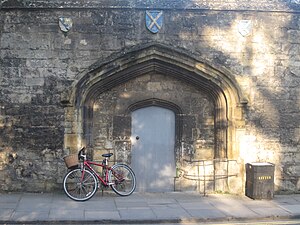 The 15th century gate of Gloucester College, surviving to the side of the current gate and bearing the arms of the abbeys of Winchcombe, St Albans and Ramsey