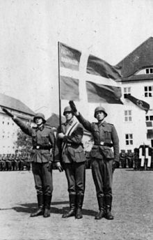 a black and white photograph of soldiers performing the "Hitler salute" beneath a Danish flag