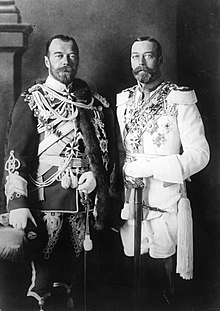 Two look-alike men. Both wear beards and are in full military regalia festooned with medals—one uniform dark, the other white.