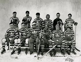 A group photograph of ten hockey players wearing horizontally striped jerseys with a maple leaf logo surrounding the letters "CAC", along with their coach
