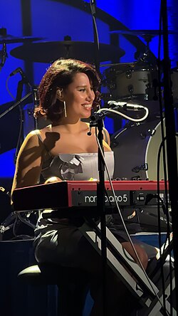 Raye smiling while performing on stage