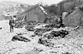 The deadly result of enfilade fire during the Dieppe Raid of 1942: dead Canadian soldiers lie where they fell. Trapped between the beach and fortified sea wall (covered with barbed wire), they made easy targets for MG 34 machineguns in a German bunker. The bunker firing slit is visible in the distance, just above the German soldier's head.