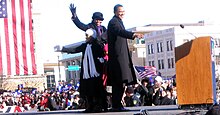 Photograph of Obama with his family in front of a crowd of people.