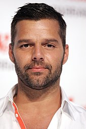 Ricky Martin, wearing a white shirt with an orange strip.