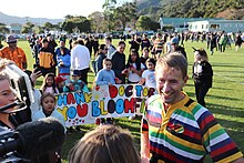 Ashley Bloomfield being interviewed by the press after the 2020 Parliamentary rugby match (children in the background are holding up large home-made posters that say "THANK YOU DOCTOR BLOOMFIELD")