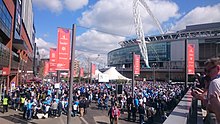 View of Wembley stadium, adjacent buildings and outdoor areas with gathered supporters