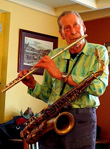 Turner playing flute, with a saxophone slung around his body
