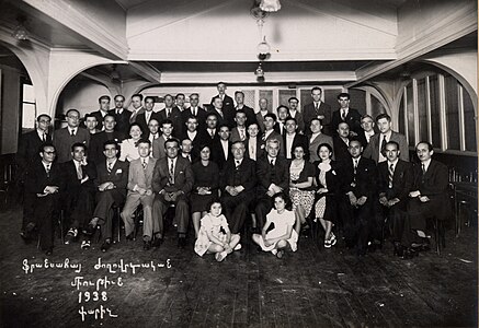 Photographie en noir et blanc d'hommes et de femmes posant sur plusieurs rangs face à l'objectif.