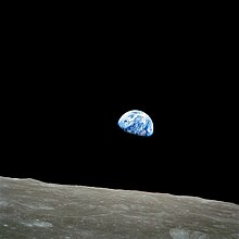 El chico azul-blanco semicirculo del Tierra, casi brillando de color na el negrura del espacio, saliendo sobre el limbo de la desolao, cratereao superficie del Luna.