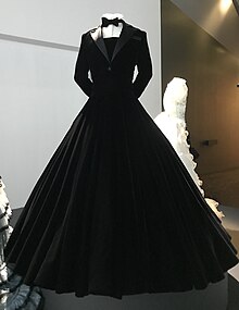 A black velvet ball gown, the top half styled like a tuxedo, with a voluminous white-trimmed skirt