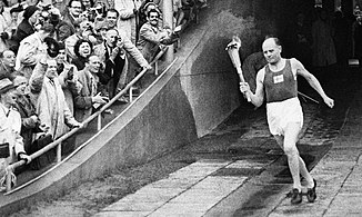 Paavo Nurmi enters the Helsinki Olympic Stadium carrying the torch during the opening ceremonies. He became the first well-known athlete to light the Olympic Flame.