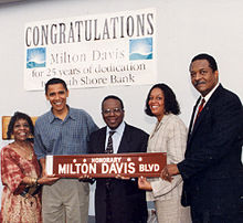 Five people carry a brown streetsign that reads "Honorary: Milton Davis Blvd."