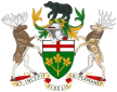 A central shield with the upper part showing the red cross of St. George and the lower part showing three golden maple leaves on a green background. There is a black bear on top of a knight's helmet above the shield with a moose to the left and a Canadian deer to the right. The province's motto "Ut incepit Fidelis sic permanet", Latin for "Loyal she began, loyal she remains" is written below the crest.