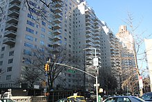 Manhattan House, a white-brick building with glass balconies, as seen from Second Avenue and 66th Street. The apartment building is to the left, and there is a traffic light across the street.