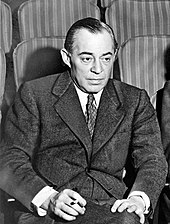 Photo of Rodgers, in middle age, seated in a theatre, wearing a suit and holding a cigarette
