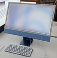 An thin iMac in blue color on a desk.