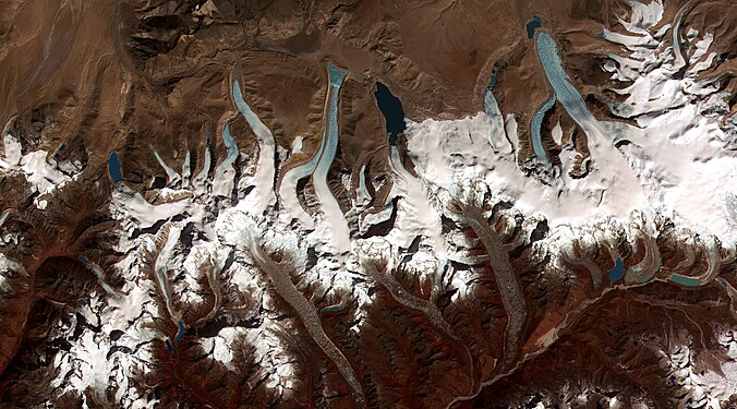 Glacier retreat is a type of glacial motion in which more material ablates from its terminus of the glacier than is replenished by flow into that region. In this region of the Bhutan-Himalaya, glacial lakes have been rapidly forming on the surface of the debris-covered glaciers and researchers have found a strong correlation between increasing temperatures and glacial retreat. (Credit: NASA & USGS.)