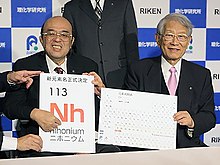 Lead researcher Kosuke Morita and Riken president Hiroshi Matsumoto from Riken showing "Nh" being added to the periodic table