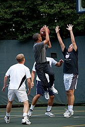 Obama about to take a shot while three other players look at him. One of those players attempts to block Obama.