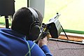 A junior shooter in Switzerland exercising bullseye shooting with a SIG 550. The rifle is equipped with a brass catcher to avoid disturbing other shooters with the ejection.