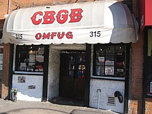 The front of the music club CBGB is shown. An awning has the letters CBGB painted on it. Below the name are the letters "OMFUG".